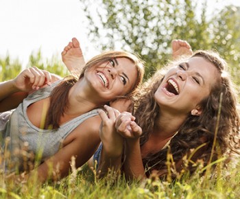 two girlfriends lying down on grass